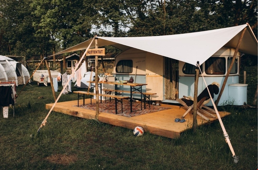 Retro caravan Huttentut op Camping de Kleine Wereld met picknickbank en buitengevoel