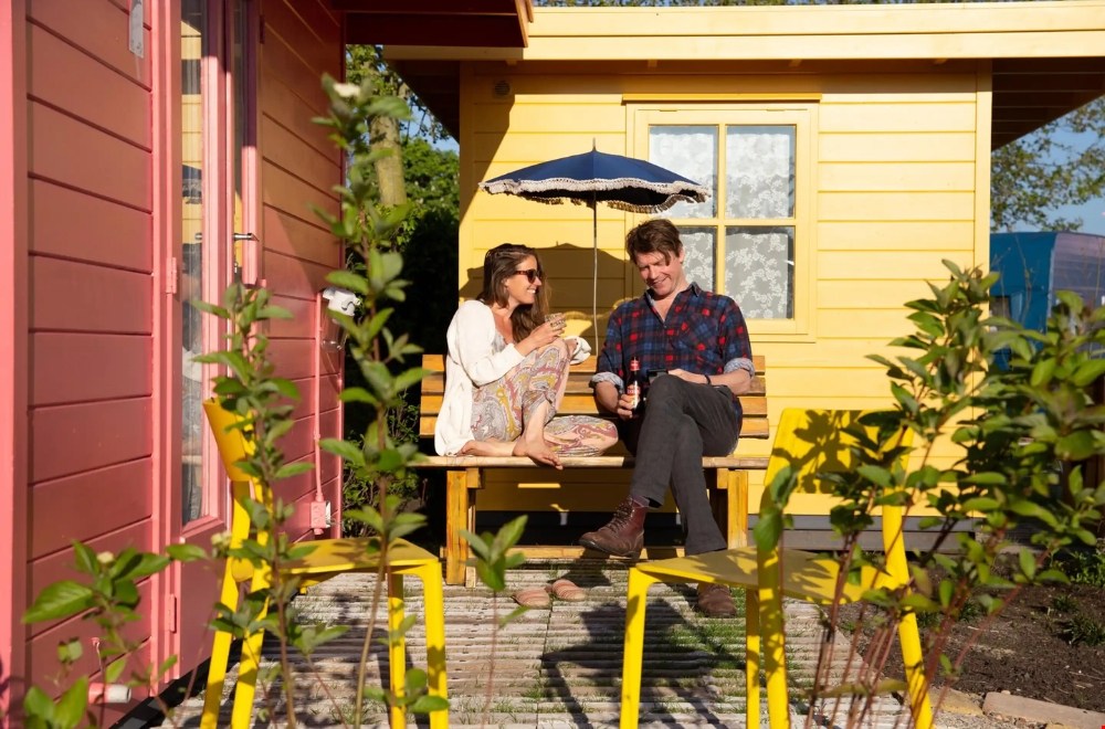 Kleurrijk vakantieadres De Tuin van Tralala met knusse huisjes, caravans en wilde bloemen.